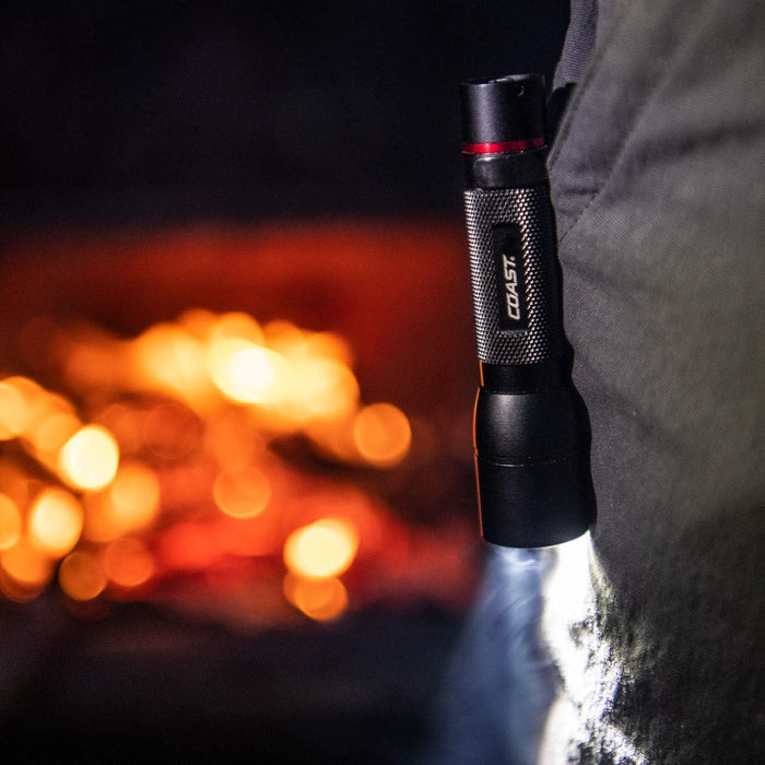 Flashlight held by a person with a blurred fiery background