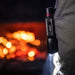 Flashlight held by a person with a blurred fiery background
