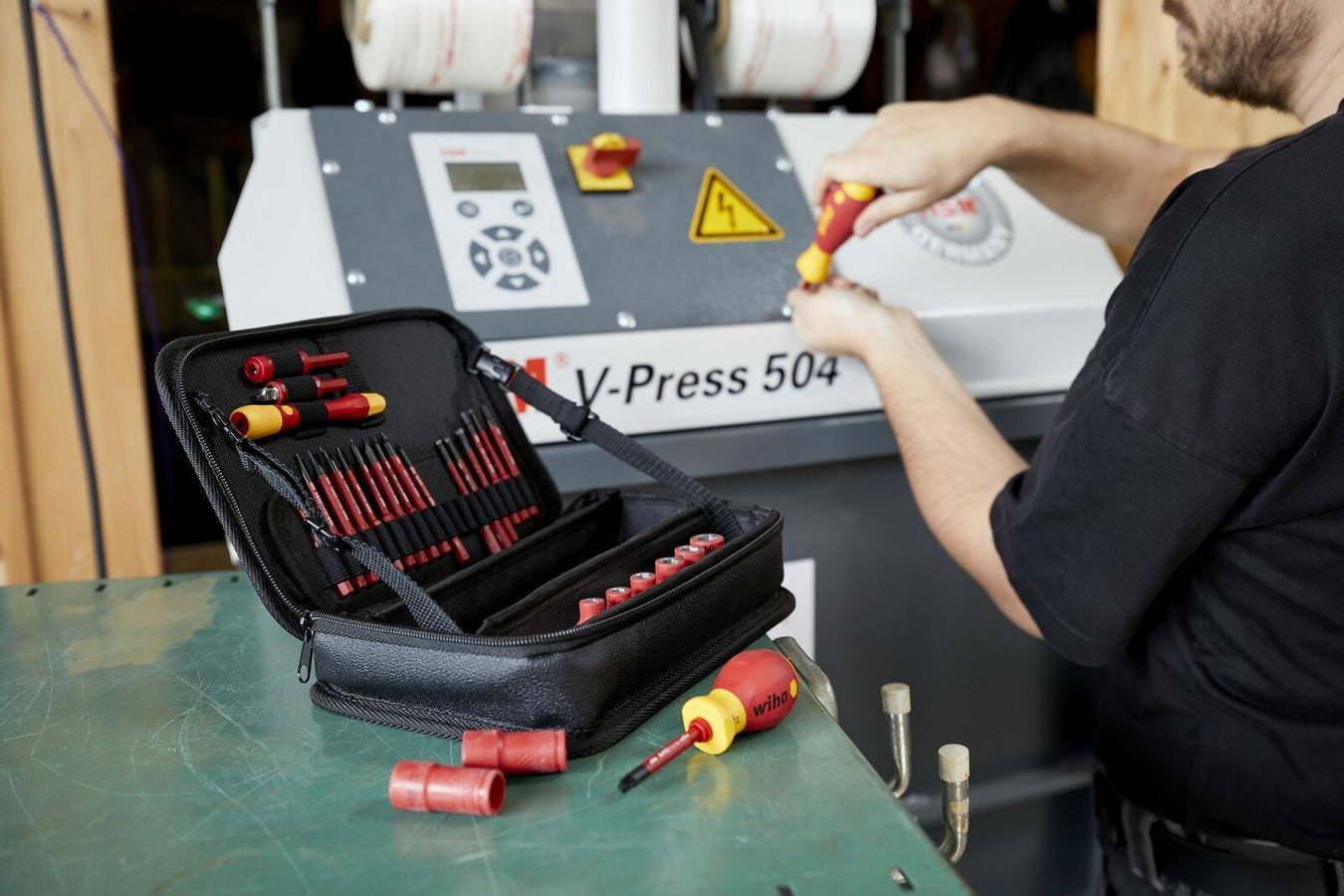 Wiha Tool kit on a green bench while someone is working in the background