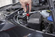 Person using a red and black screwdriver in a car's open hood